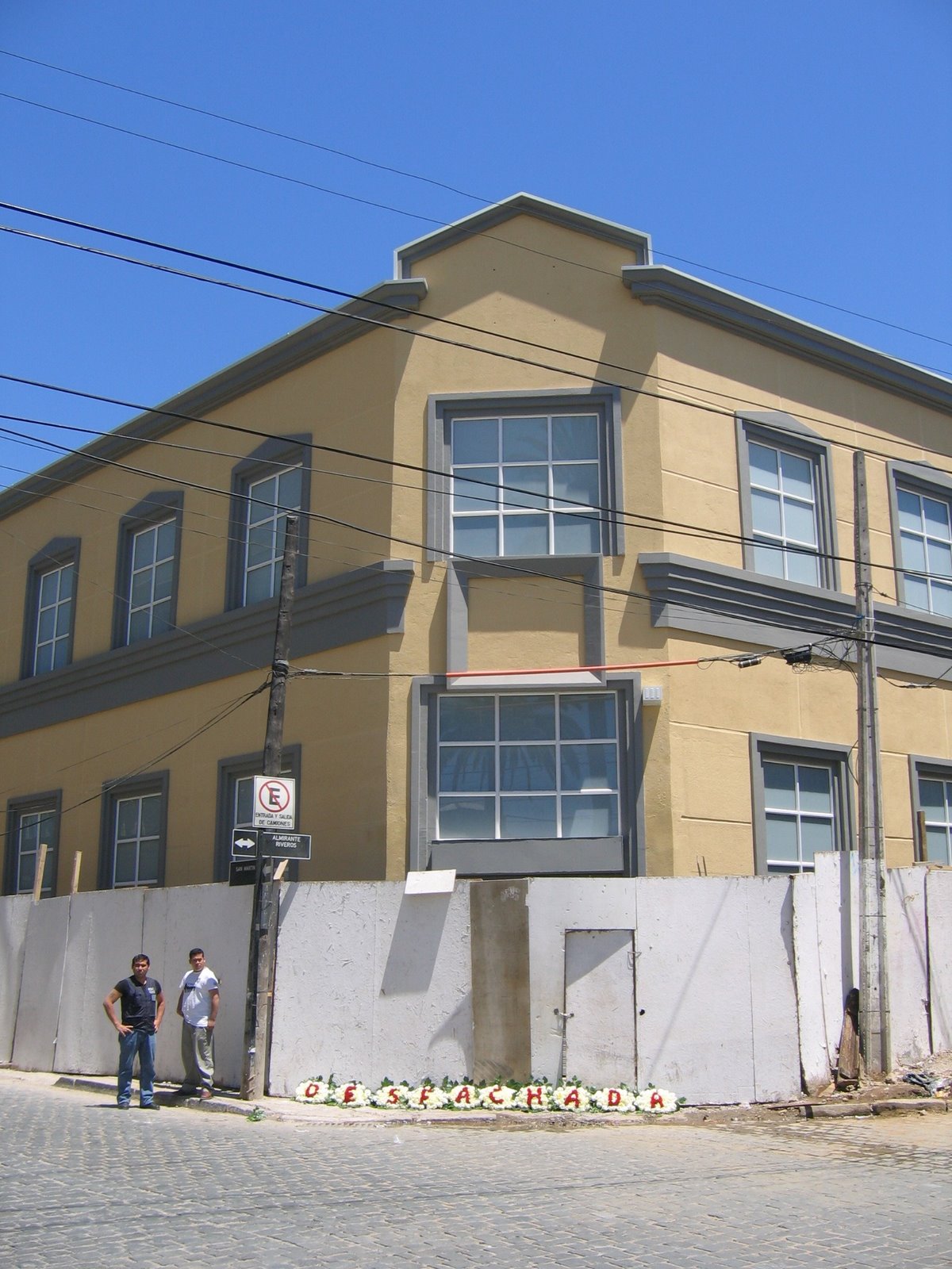 Ofrenda floral con la palabra «DESFACHADA» sobre el cierre perimetral de una construcción, Valparaíso