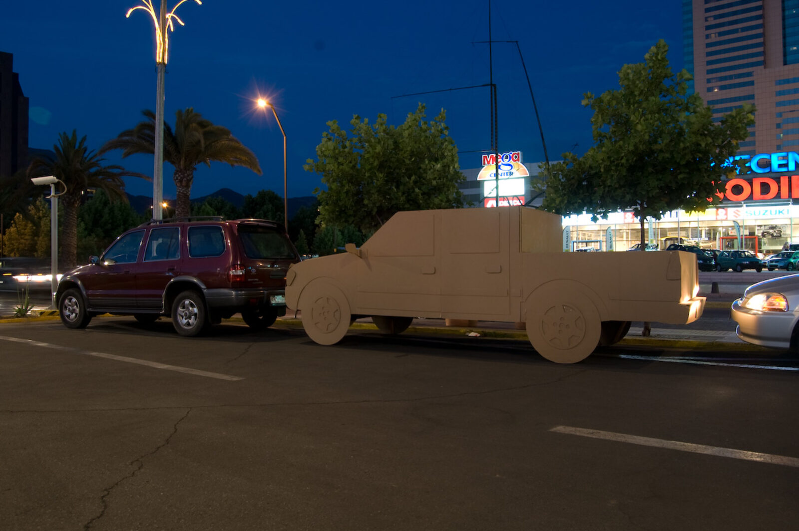 Pieza de Cartón, camioneta LUV estacionada de noche frente a Parque Arauco