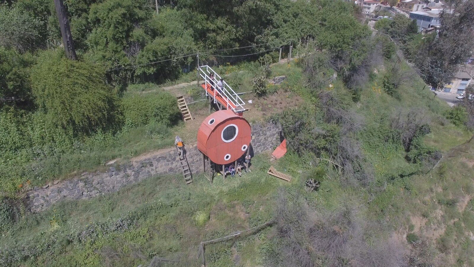 Vista aérea de El Jardín de las Delicias, estructura circular roja adosada a un muro del Cerro Delicias, Valparaíso