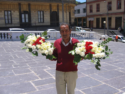 Hombre sosteniendo un arreglo floral con letras en una plaza