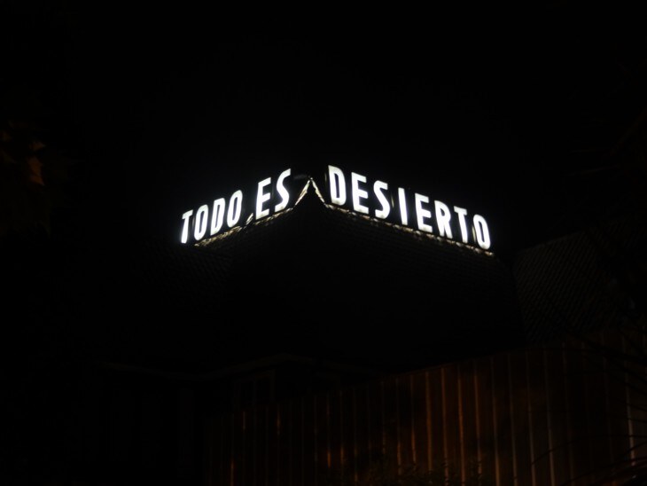 Todo es Desierto, el letrero encendido de cerca, contra el cielo nocturno