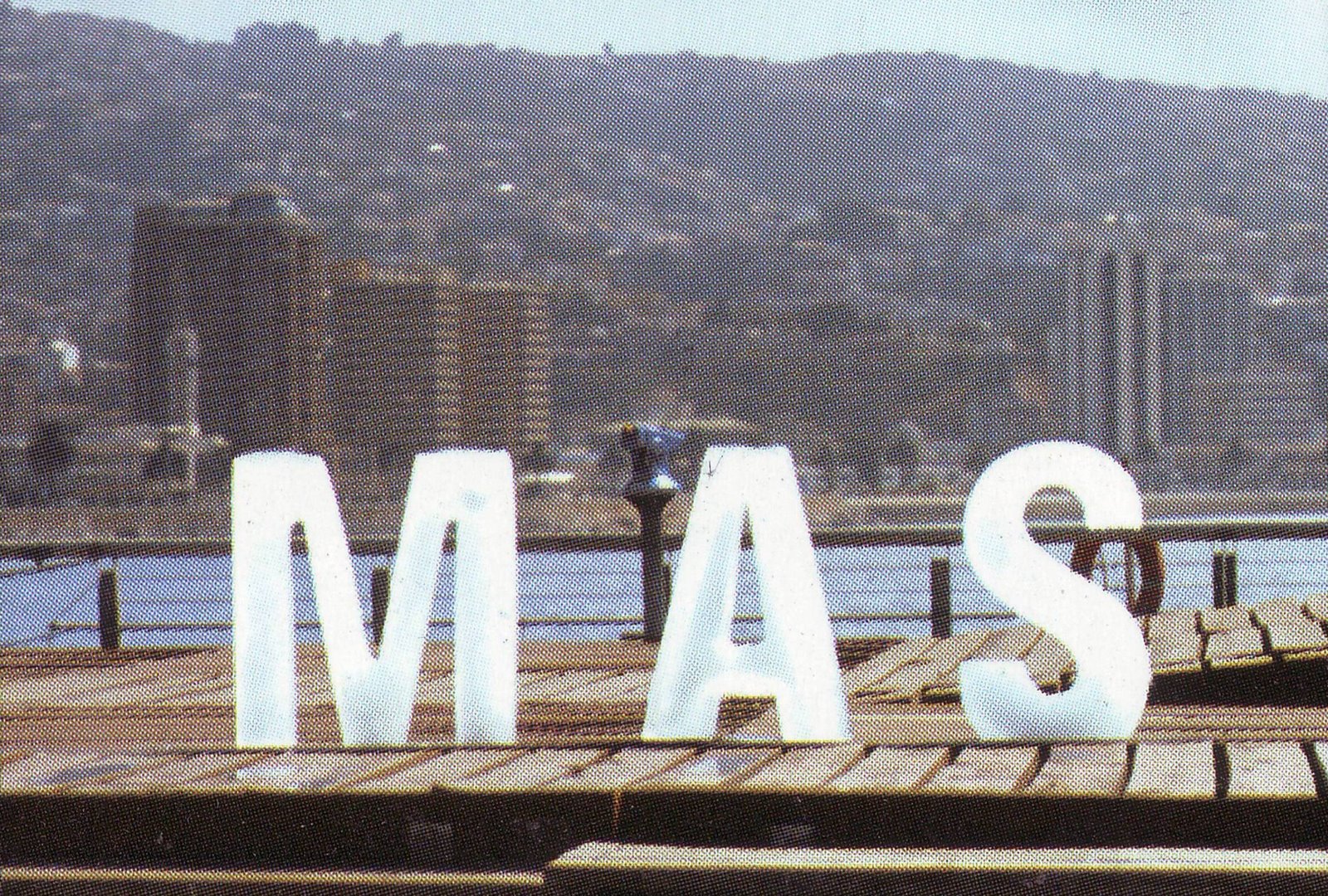Letra «MAS» instalada sobre un muelle, con la bahía de Valparaíso al fondo