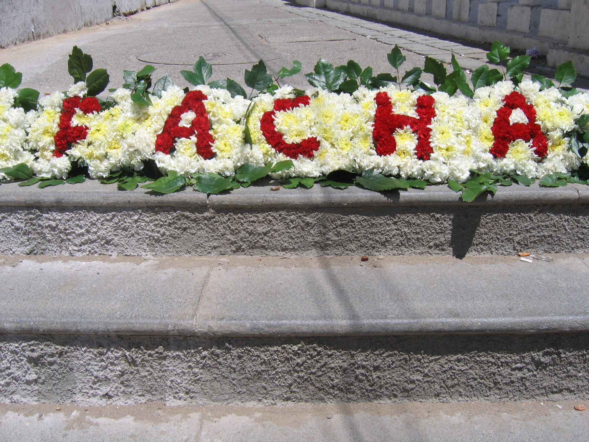Detalle de la ofrenda floral con la palabra «DESFACHADA»