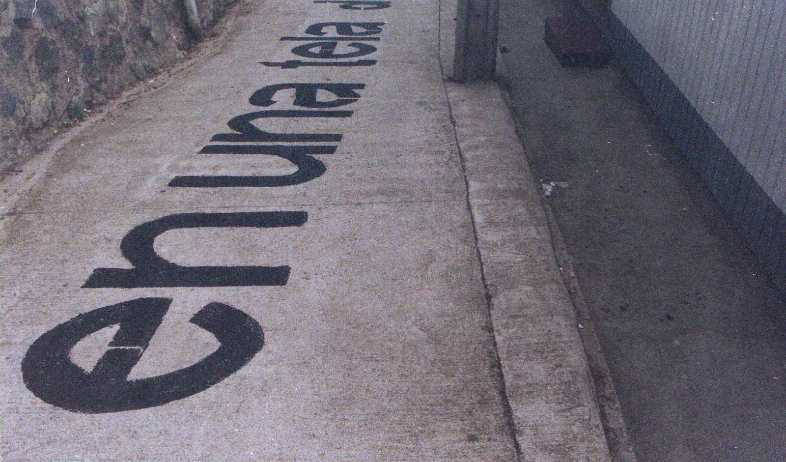 Escritura invertida «es una tela de» pintada sobre el pavimento de un pasaje