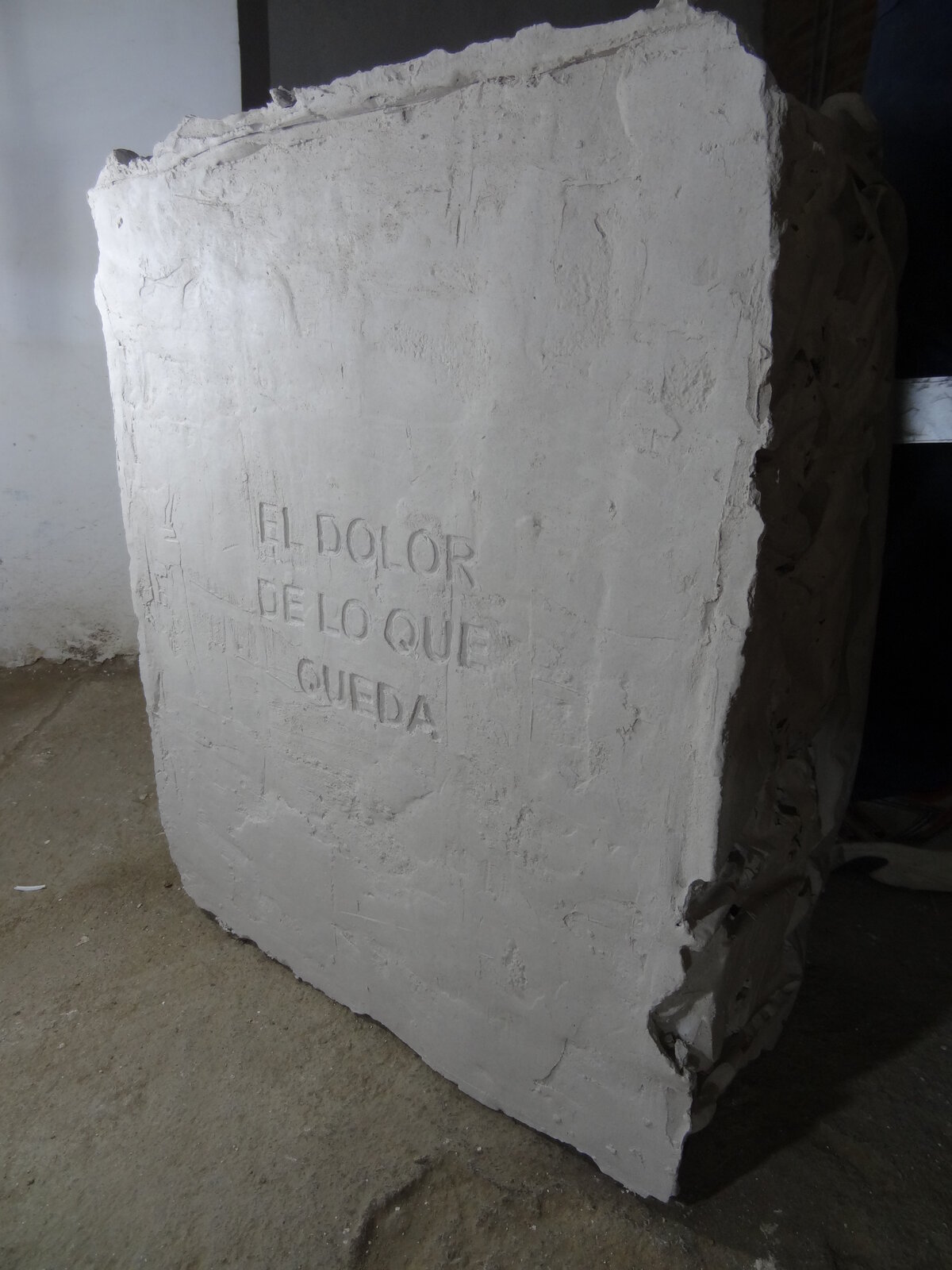 Detalle del bloque de yeso con el texto El dolor de lo que queda